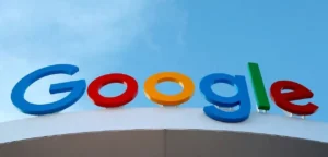 Logo Google en lettres tridimensionnelles colorées sur le toit d'un bâtiment sous un ciel bleu